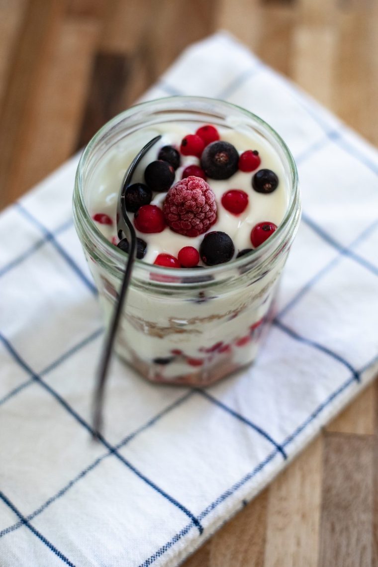 Yoghurt and frozen berry crunch in a glass jar - stock photo