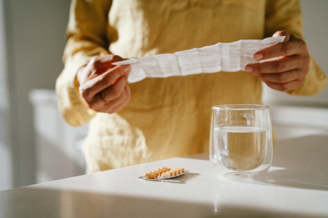 A woman standing at a table with green pills in her hand