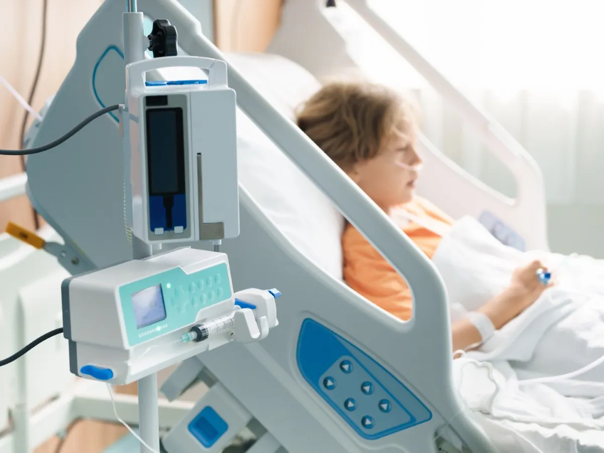 A stock image of a sick child in a hospital room with an oxygen tube and IV line.