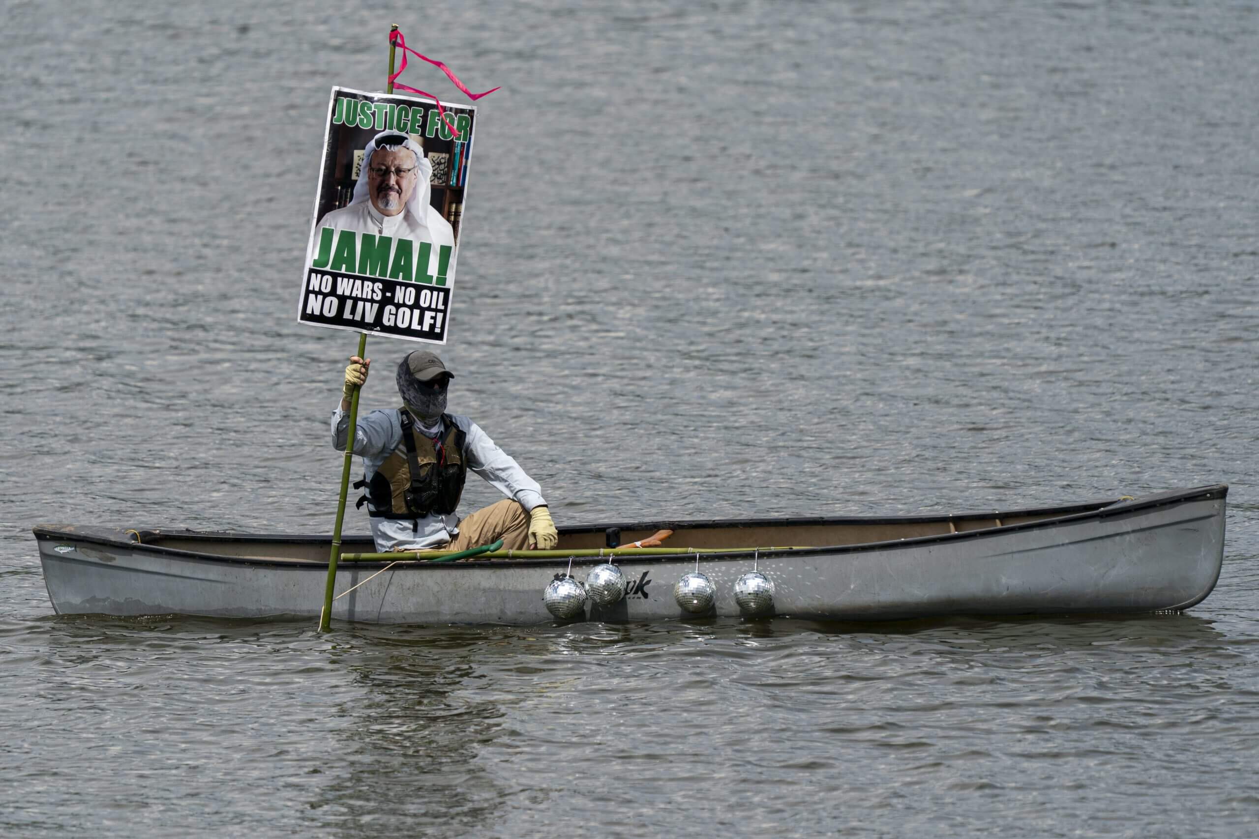A protester on a canoe near the LIV Golf Virginia event holds a sign protesting the tour's Saudi links.