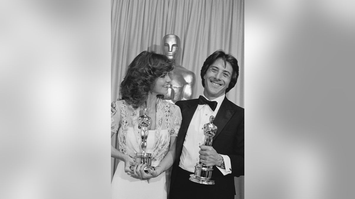 Actress Sally Field and actor Dustin Hoffman smiling and holding Oscars at awards ceremony