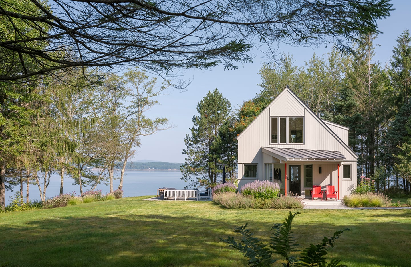 Red posts at the entry are an ode to the homeowner’s mom and also reference the red tinge of new Eastern white-cedar planks that have been stained gray, replacing the previous brown clapboard siding.