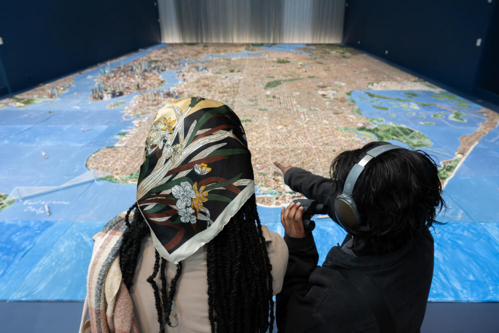 People look at the model while holding binoculars. (Filip Wolak/Museum of the City of New York)