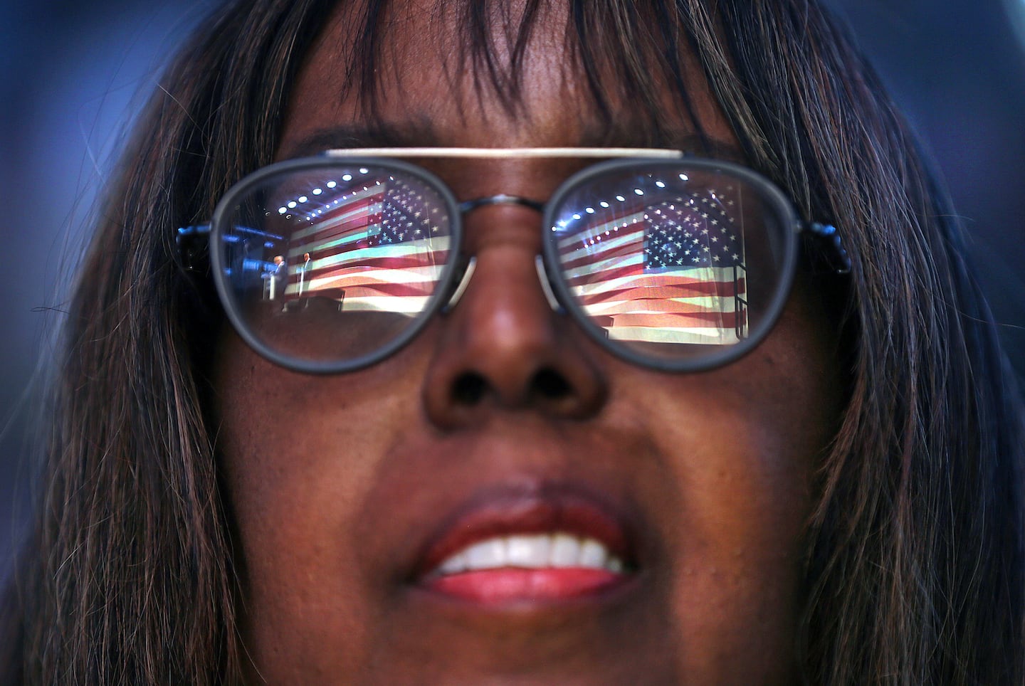 A huge flag is reflected in the glasses of Melanie Thompson, a delegate from Lexington, during the Massachusetts Democratic Party's convention on Saturday.