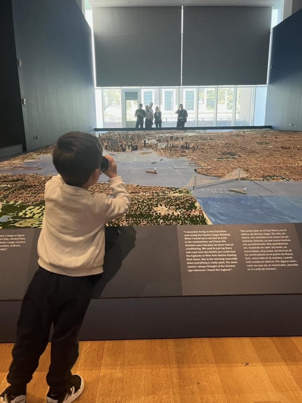 Boy uses binoculars to take in Joe Macken's model at the Museum of the City of New York. (Robin Young/Here & Now)