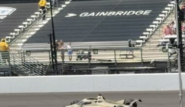 Race car on a track with spectators in the stands; 'GAINBRIDGE' painted on the surface ahead of the car.
