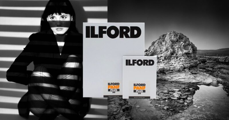 A woman with dramatic light and shadow lines across her face and legs sits next to two boxes labeled "ILFORD PANF PLUS 50." In the background is a black and white rocky landscape with water.