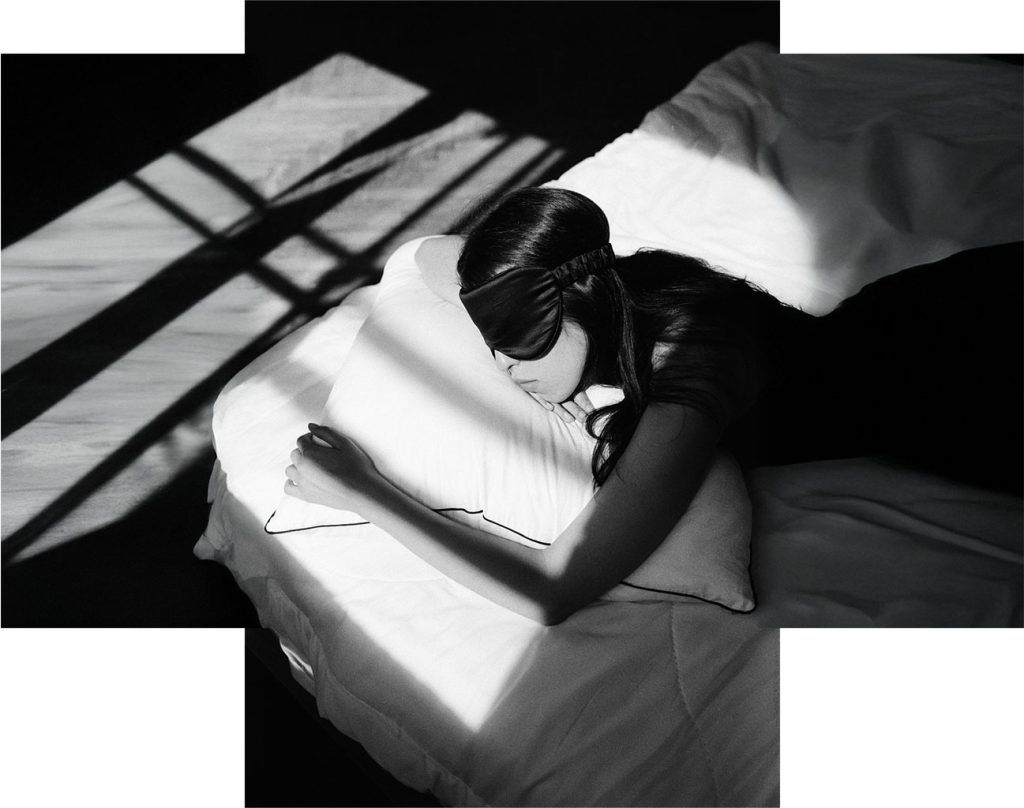person asleep in bed wearing eye mask