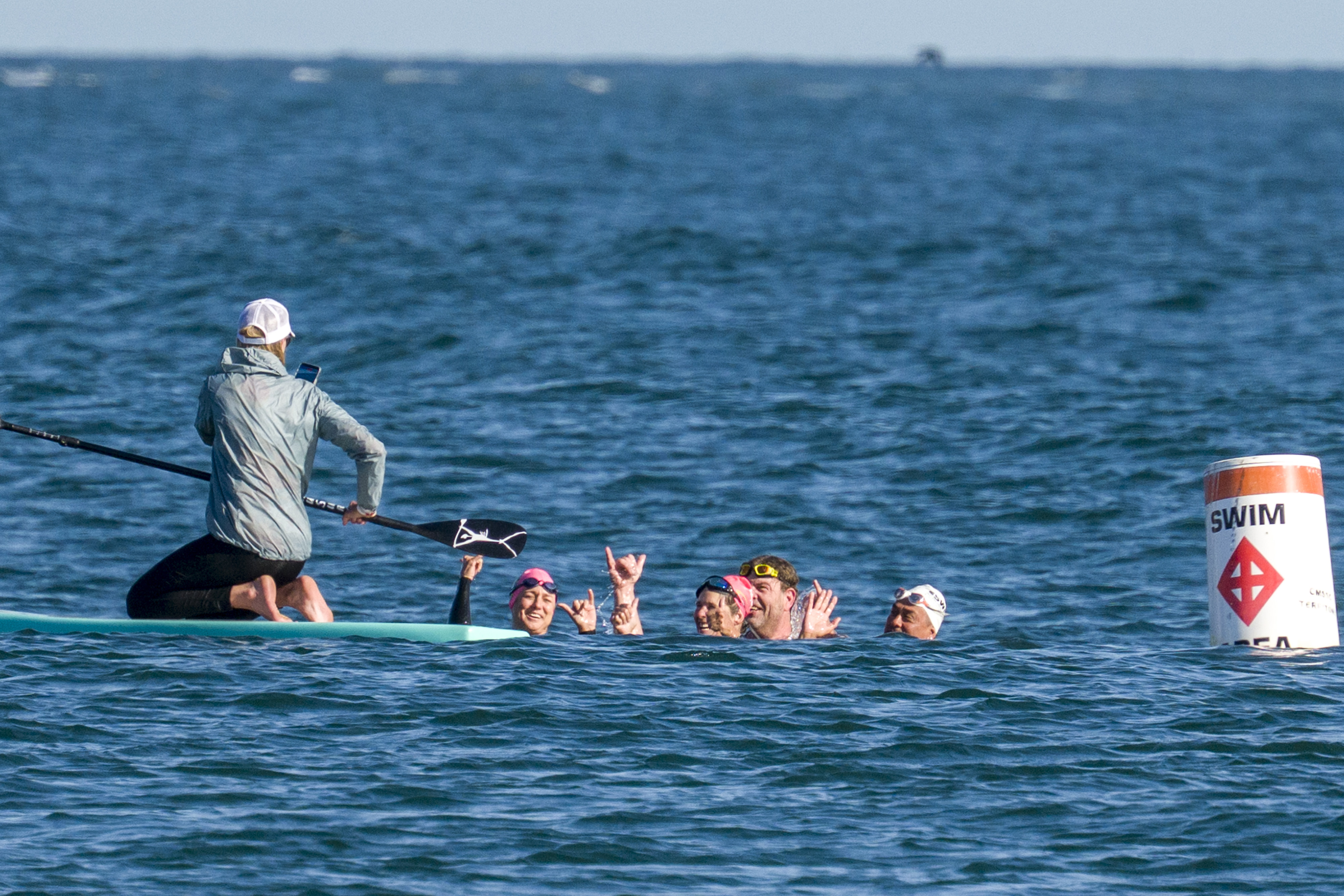 Kristiina Beary, on surfboard, takes a photo of swimmers, from...