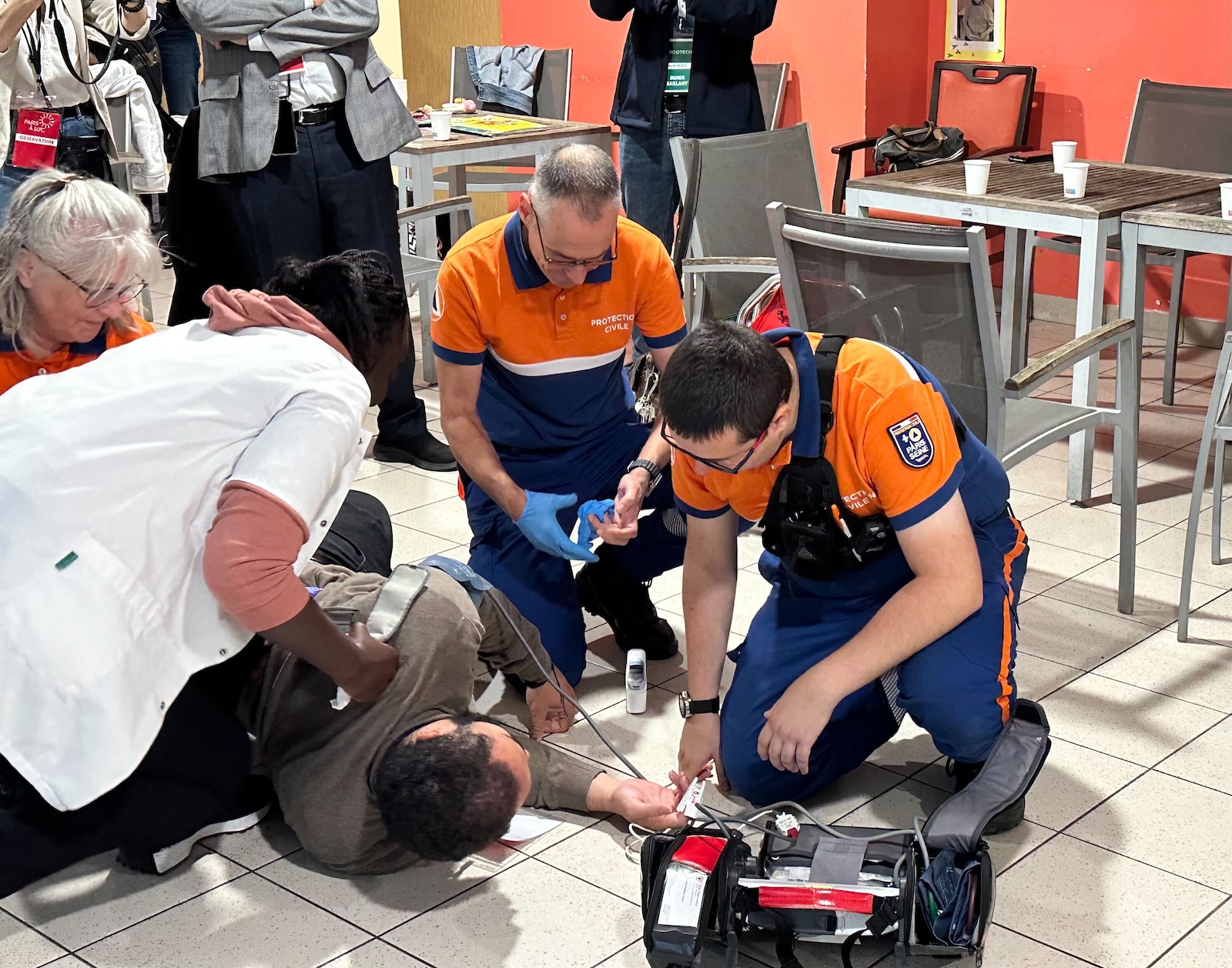 medics in orange shirts attend to a collapsed person