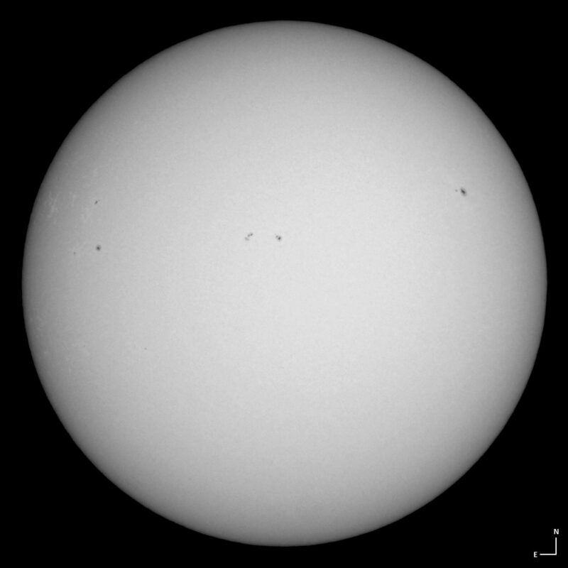 The sun, seen as a large white sphere with small dark spots.