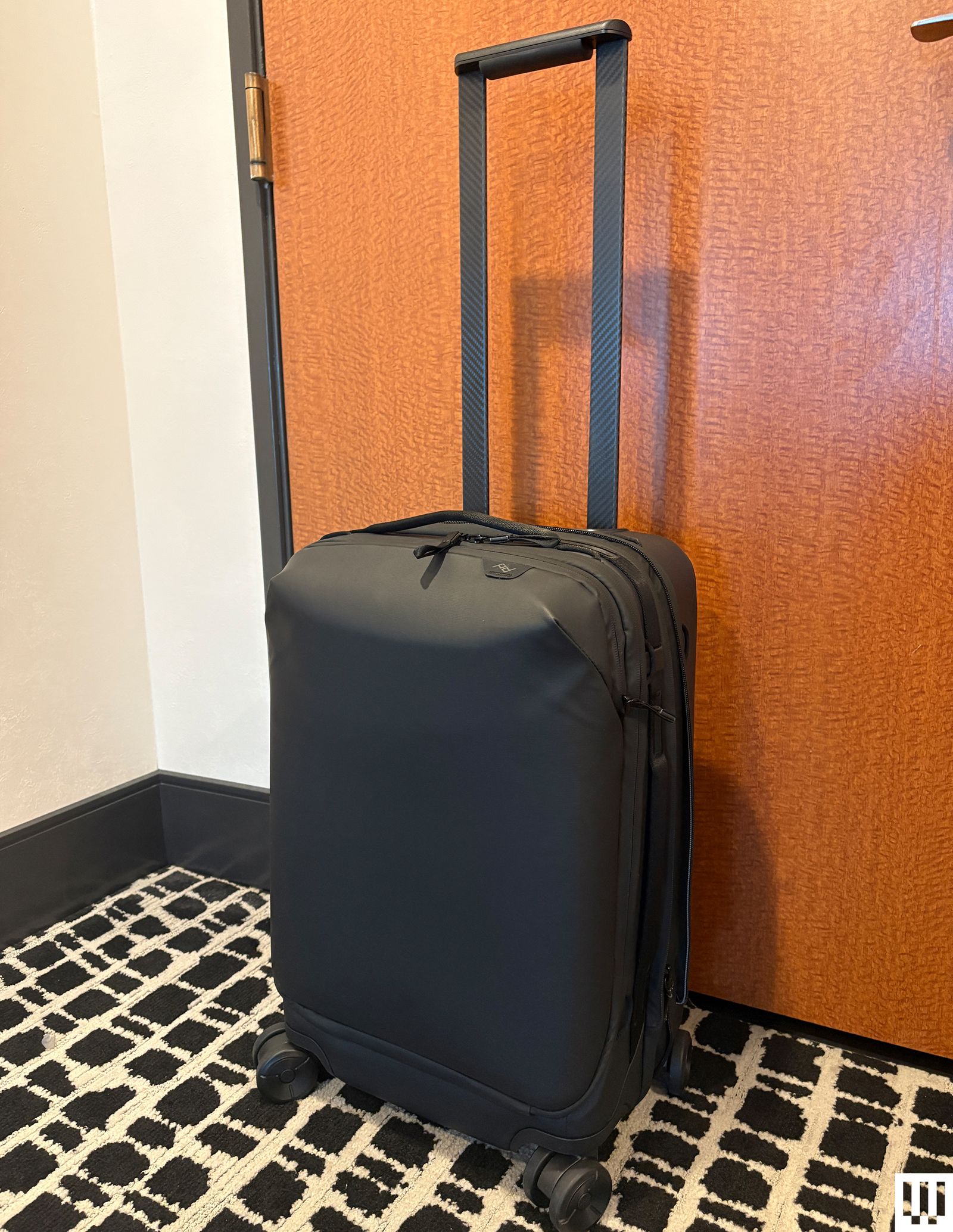 Peak Design Roller Pro black rectangular luggage with wheels and the handle extended upwards