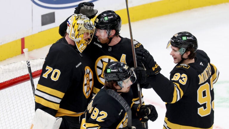 Boston Bruins goaltender Joonas Korpisalo (70) with centers Elias Lindholm (28), Marat Khusnutdinov (92) and Fraser Minten (93) celebrate after their team's win over the Pittsburgh Penguins in an NHL hockey game Sunday, Jan. 11, 2026, in Boston.