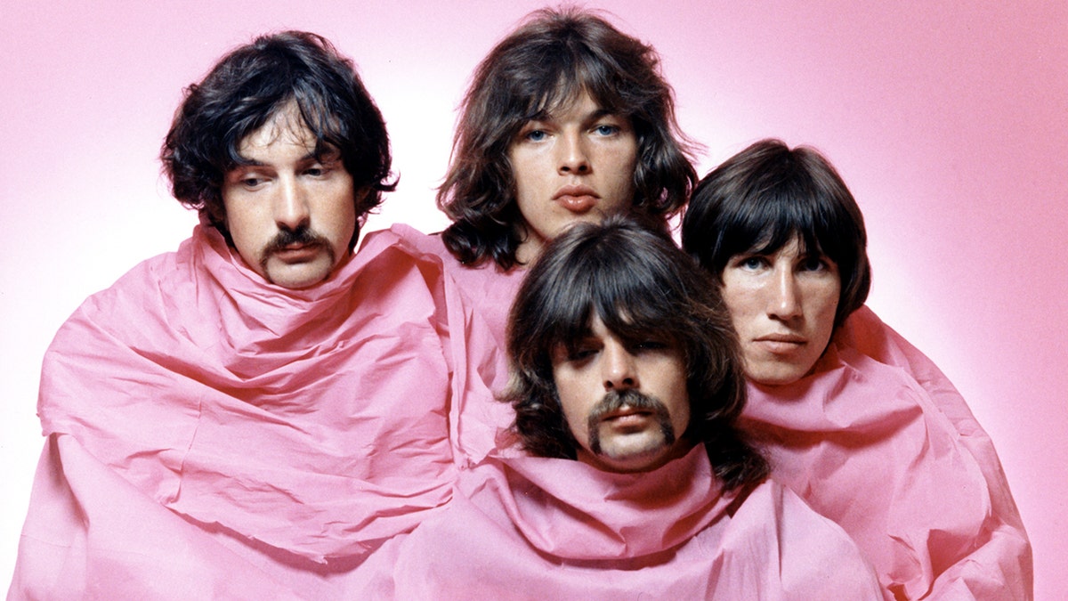 Pink Floyd members Nick Mason Dave Gilmour Rick Wright Roger Waters posing shrouded in pink.