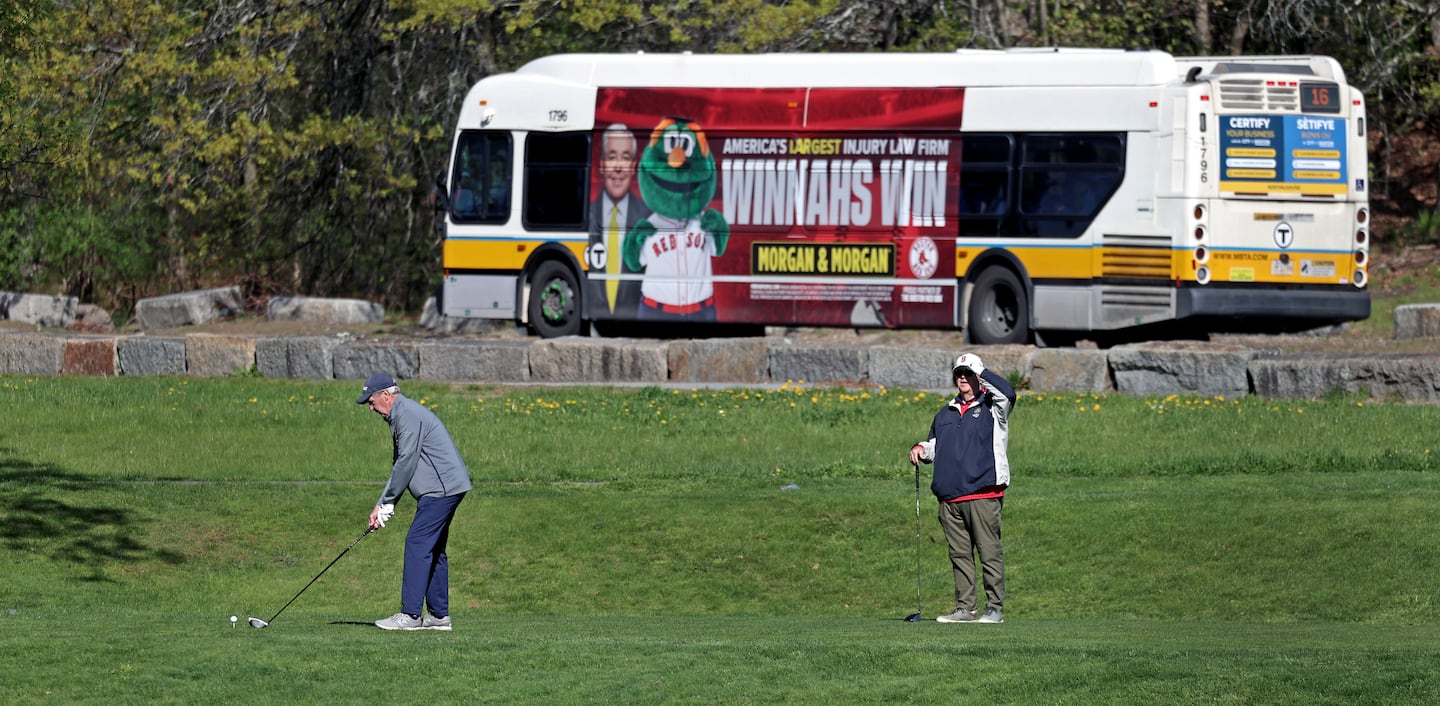 A bus passed by as Joe Renehan prepared to tee off at the William J. Devine Golf Course.