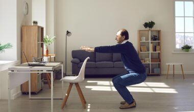 Senior Man Performing Squat Exercise by Desk