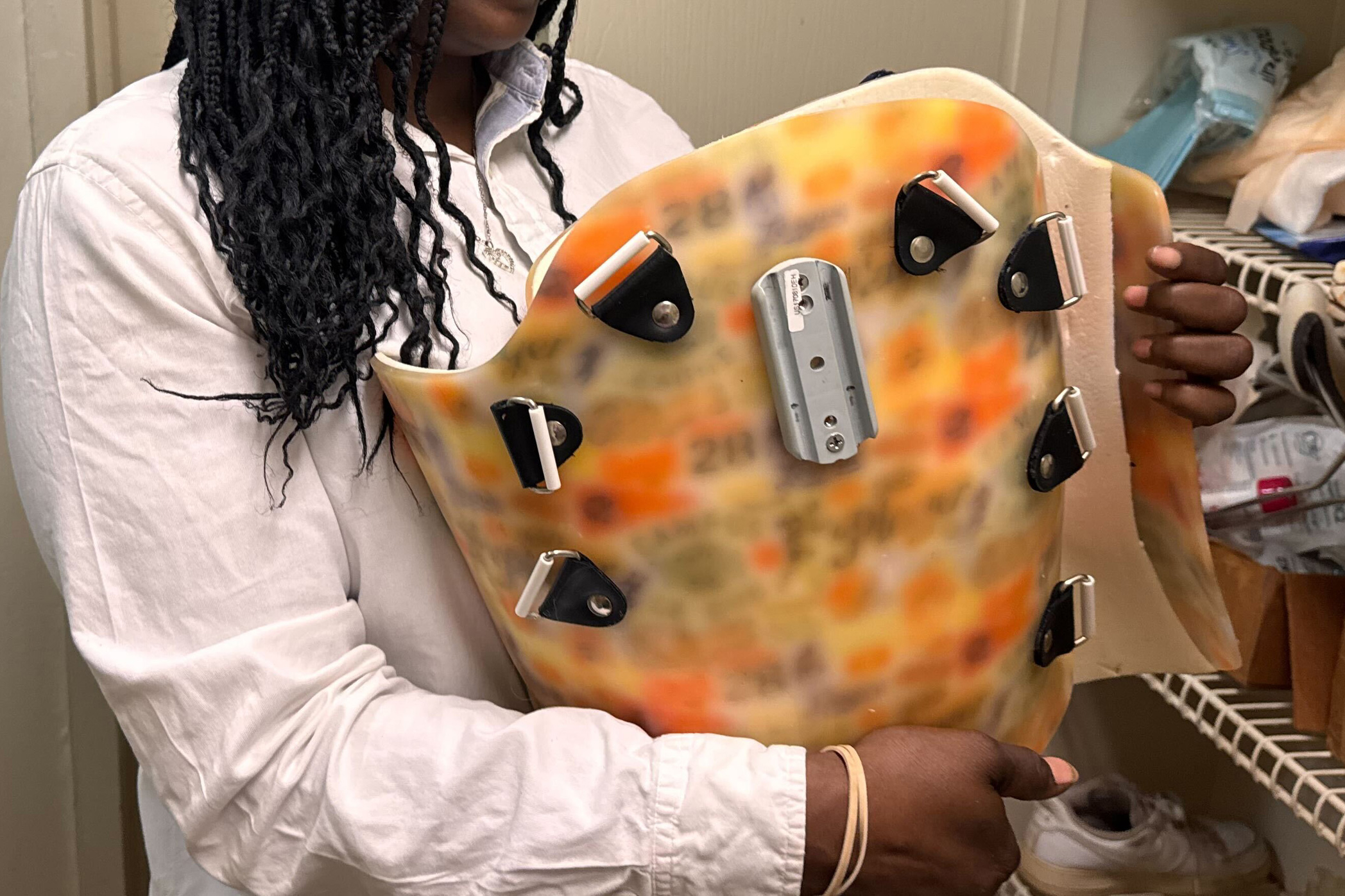 A woman, photographed from the shoulders down, holds a piece of medical equipment that was once used by her son.