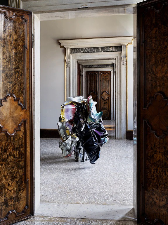 Abstract sculpture in a corridor with ornate doors and marble floors, creating a dramatic and artistic visual effect.