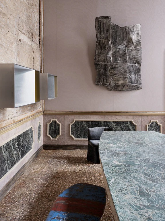 Modern interior with textured walls, marble table, abstract wall art, and sleek metal shelving in an elegant setting.