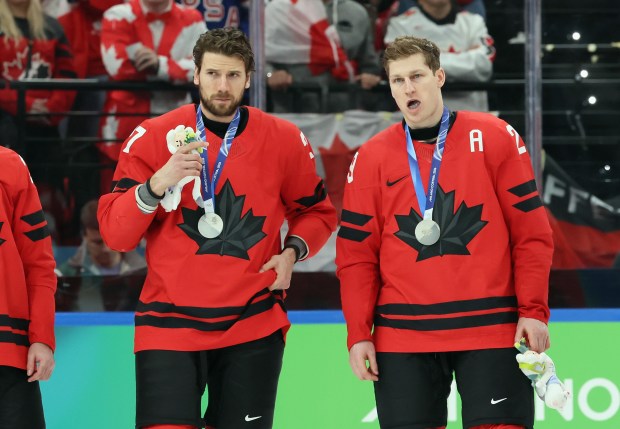 MILAN, ITALY - FEBRUARY 22: (l-r) Shea Theodore #27 and Nathan MacKinnon #29 of Team Canada stand with their silver medals following the Men's Gold Medal match between Canada and the United States on day 16 of the Milano Cortina 2026 Winter Olympic games at Milano Santagiulia Ice Hockey Arena on February 22, 2026 in Milan, Italy. The United States defeated Canada 2-1 in overtime. (Photo by Bruce Bennett/Getty Images)