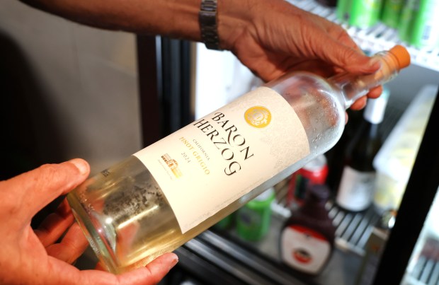 Rabbi Paul Plotkin, a kosher supervisor, examines a wine bottle for a kosher certification label at Ben's Kosher Delicatessen in Boca Raton on Monday, April 20, 2026. (Carline Jean/South Florida Sun Sentinel)