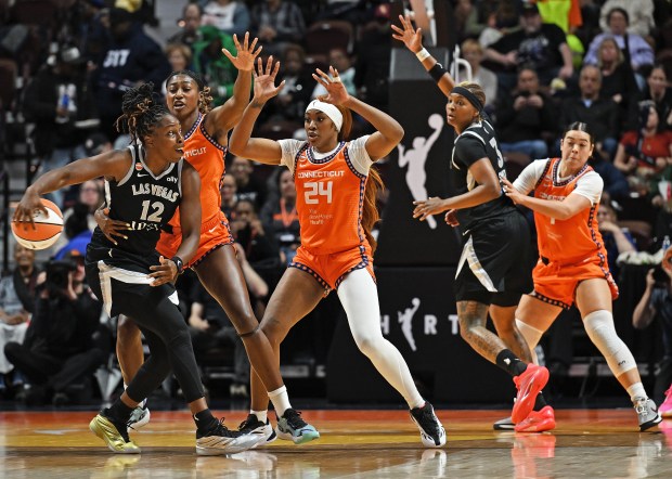 Chelsea Gray #12 of the Las Vegas Aces makes a no-look pass to teammate Nalyssa Smith #3 as Kennedy Burke #25, Aneesah Morrow #24, and Charlisse Leger-Walker #4 of the Connecticut Sun defend in the first half at Mohegan Sun Arena on May 13, 2026 in Uncasville. (Sean D. Elliot/Getty Images)