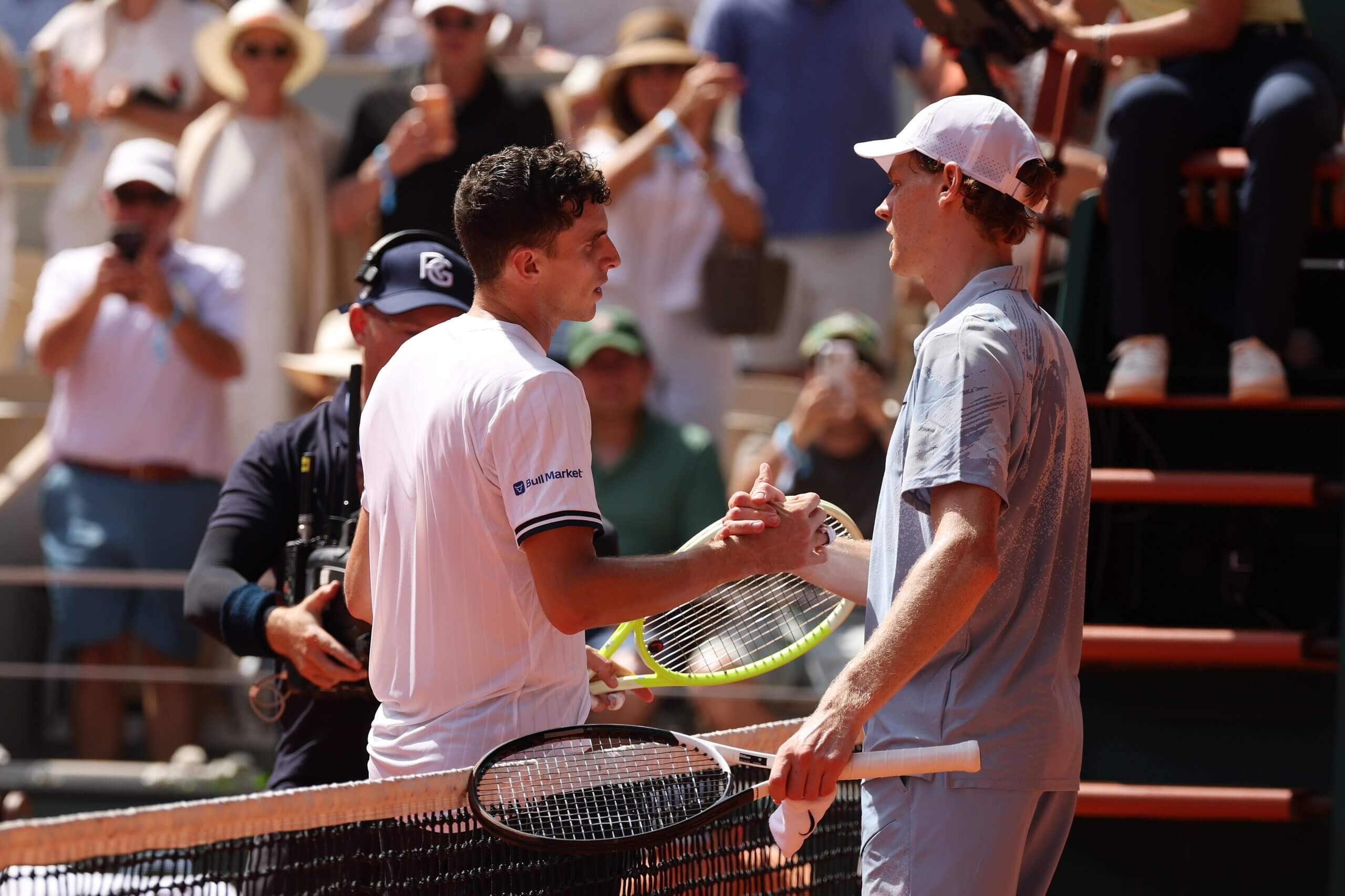 Juan Manuel Cerúndolo and Jannik Sinner shake hands over a net.
