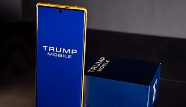 A gold-trimmed smartphone with 'TRUMP MOBILE' displayed on its blue screen stands next to a matching box.