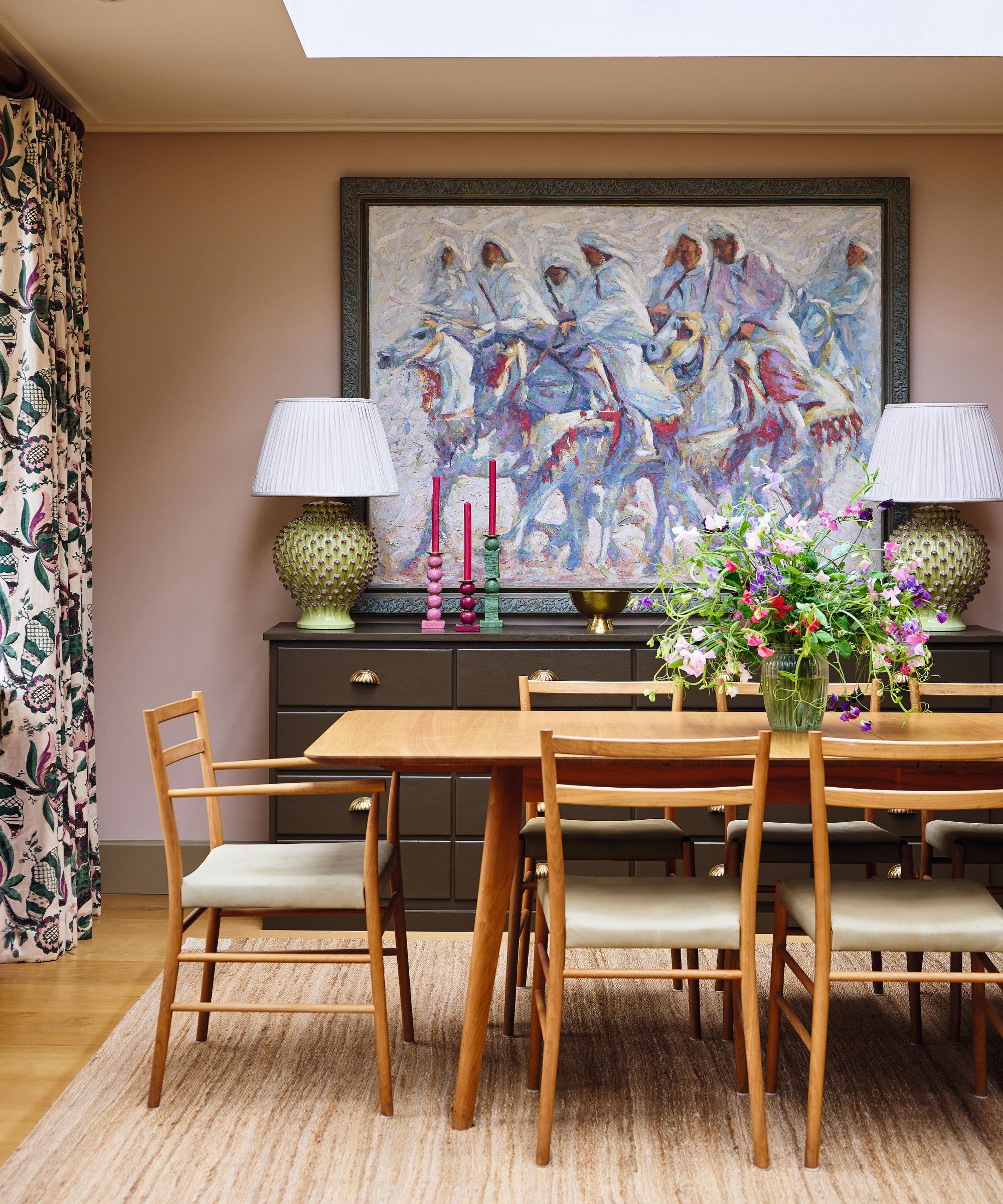 a pink dining area in a london home with a large Moroccan painting and wooden furniture