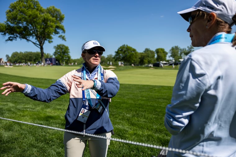 Villanova's Courtney Obregon, one of the many PGA Championship volunteers from the area, teaches Kathy Leidheiser, of Glen Mills, what to look out for as a marshal on the 18th hole at Aronimink.