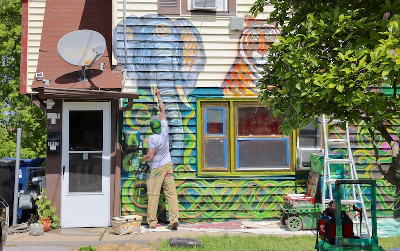 Artist David Smart is painting zoo animals on the exterior of this rental property at 521 S. Wilbur Ave.