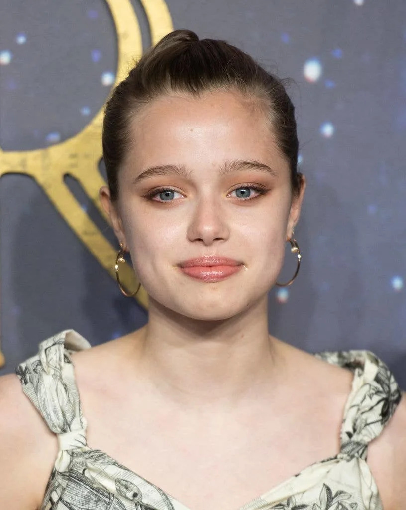 Close-up of Shiloh Jolie wearing a floral dress and gold hoop earrings on the red carpet