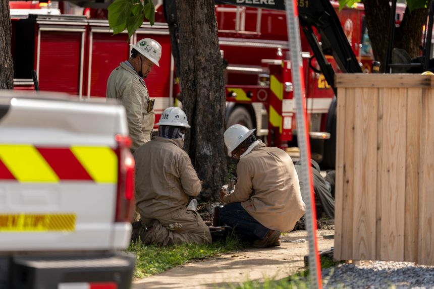Energy employees work at the scene of a large fire at an apartment complex in Dallas on Thursday.