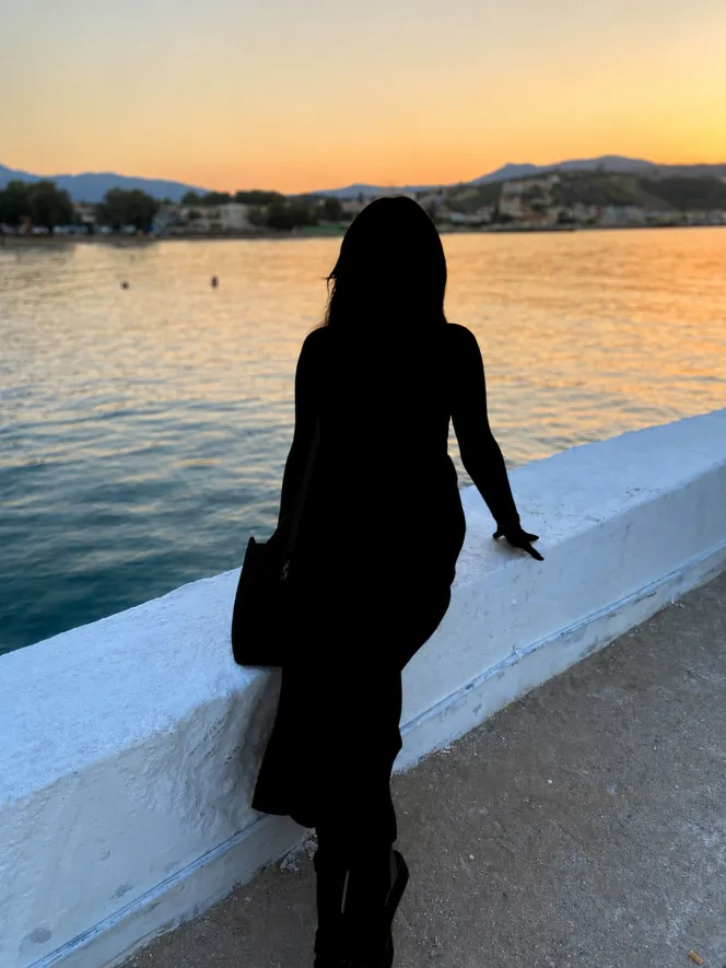 Silhouette of a person by the water at sunset.