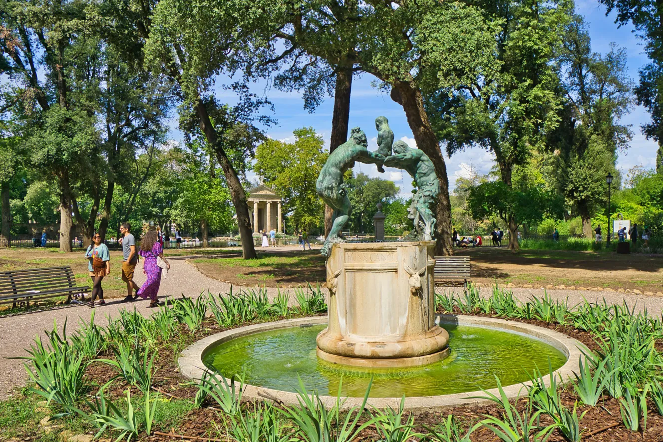 Pedestrians at a small fountain in the Villa Borghese.
