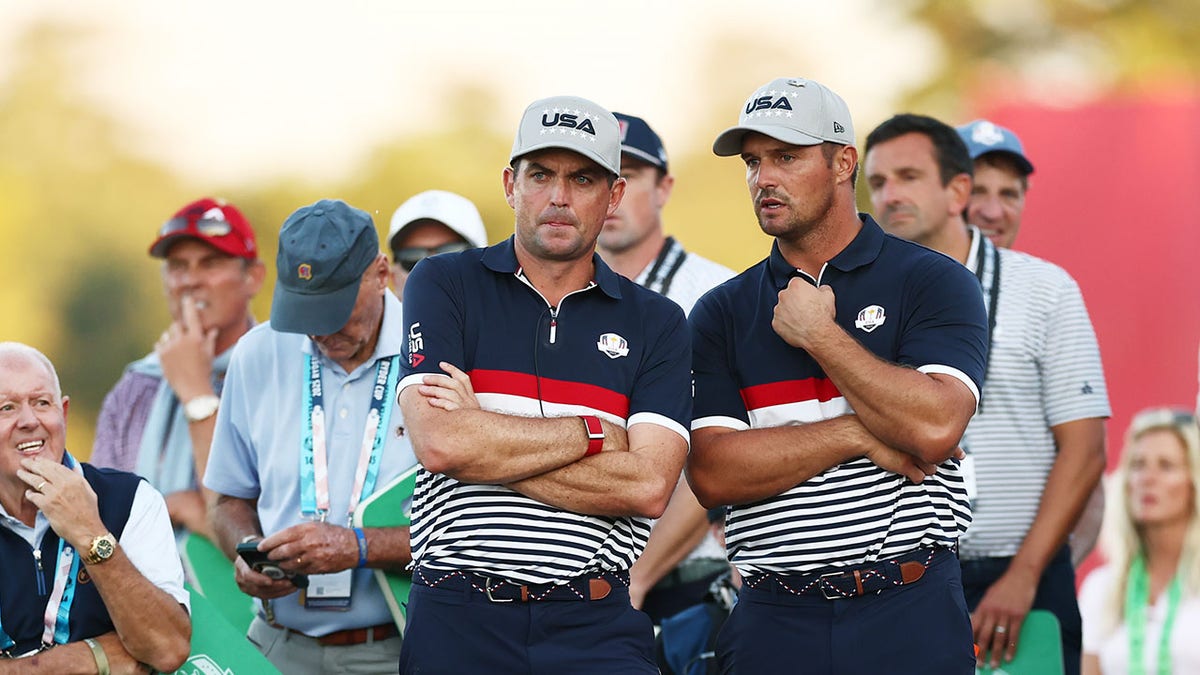 Bryson DeChambeau and Keegan Bradley standing on the 18th hole green at Bethpage State Park Golf Course