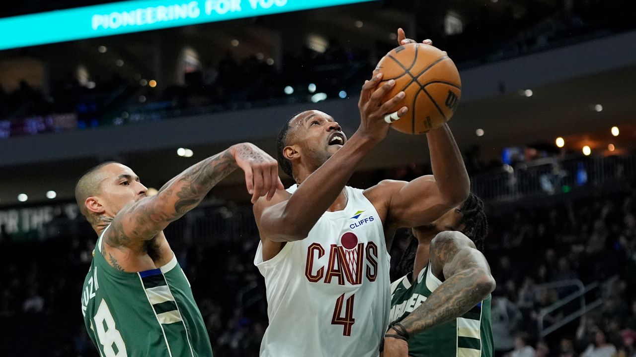 Cleveland Cavaliers' Evan Mobley (4) shoots between Milwaukee Bucks' Kyle Kuzma (18) and Kevin Porter Jr. during the first half of an NBA basketball game Tuesday, March 17, 2026, in Milwaukee.