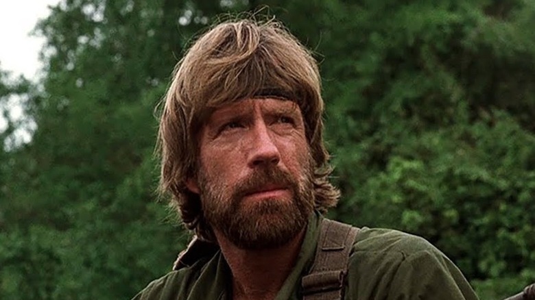 James Braddock (Chuck Norris) standing in front of some trees in 