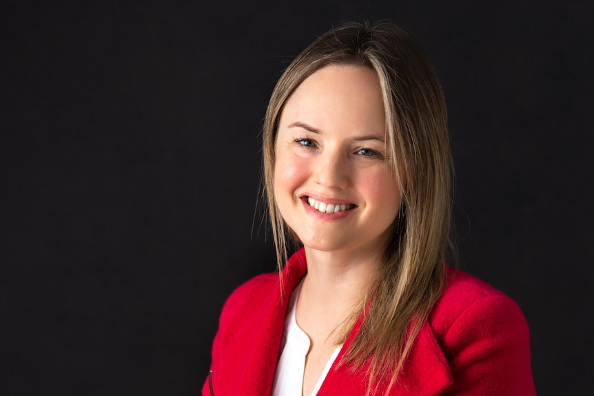 A portrait of a woman with blonde hair wearing a red blazer smiling.