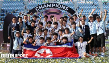 Naegohyang pose for a team photo with the North Korean flag