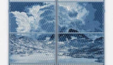 a large denim wall sculpture by Nick Doyle of a landscape behind a chain link fence