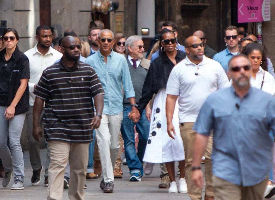 Barack Obama (C,L), his wife Michelle (C,R) and US director Steven Spielberg (C) walk in a street of Barcelona on April 28, 2023