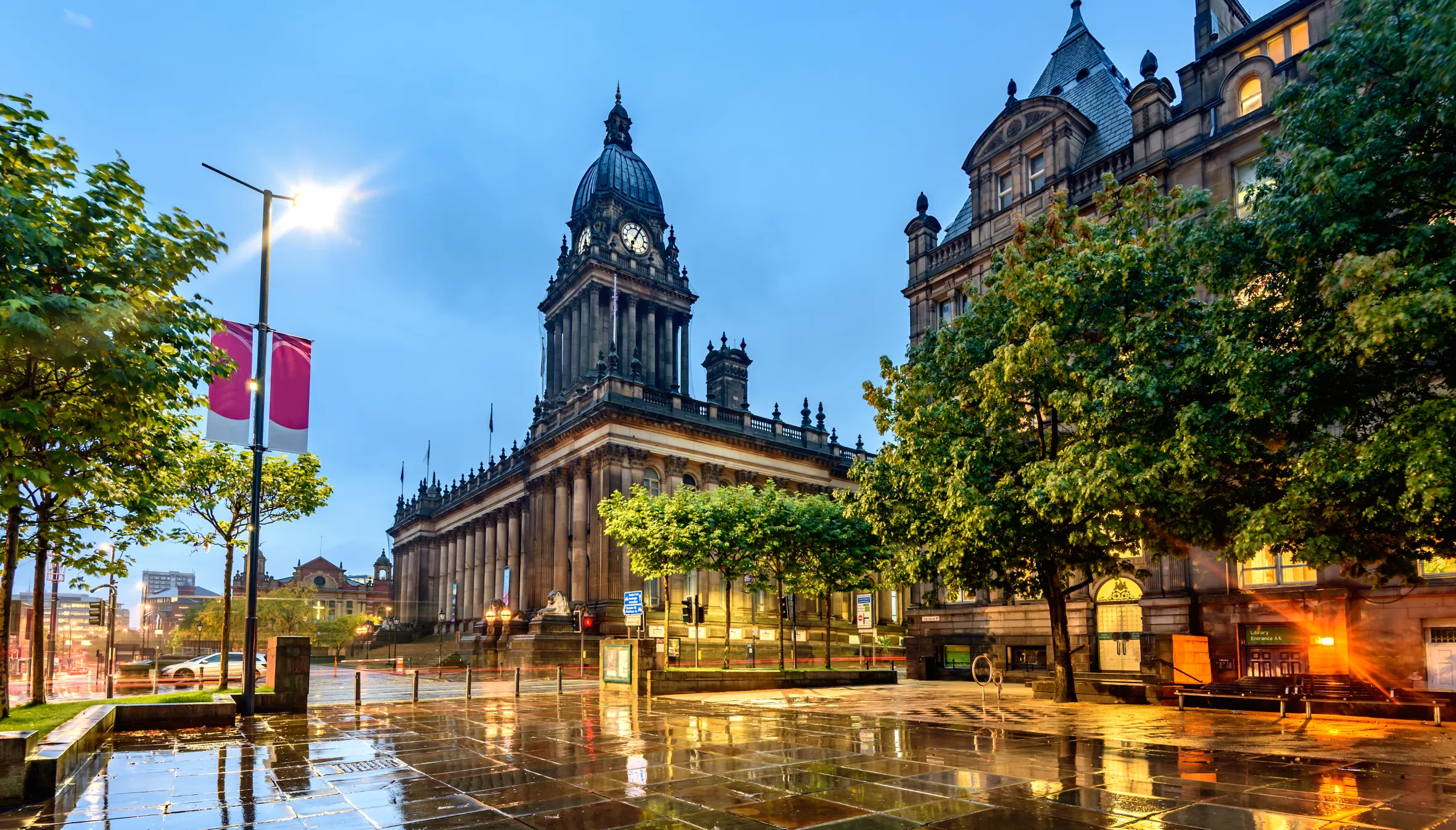 Leeds Town Hall at night with wet paving reflecting city lights.