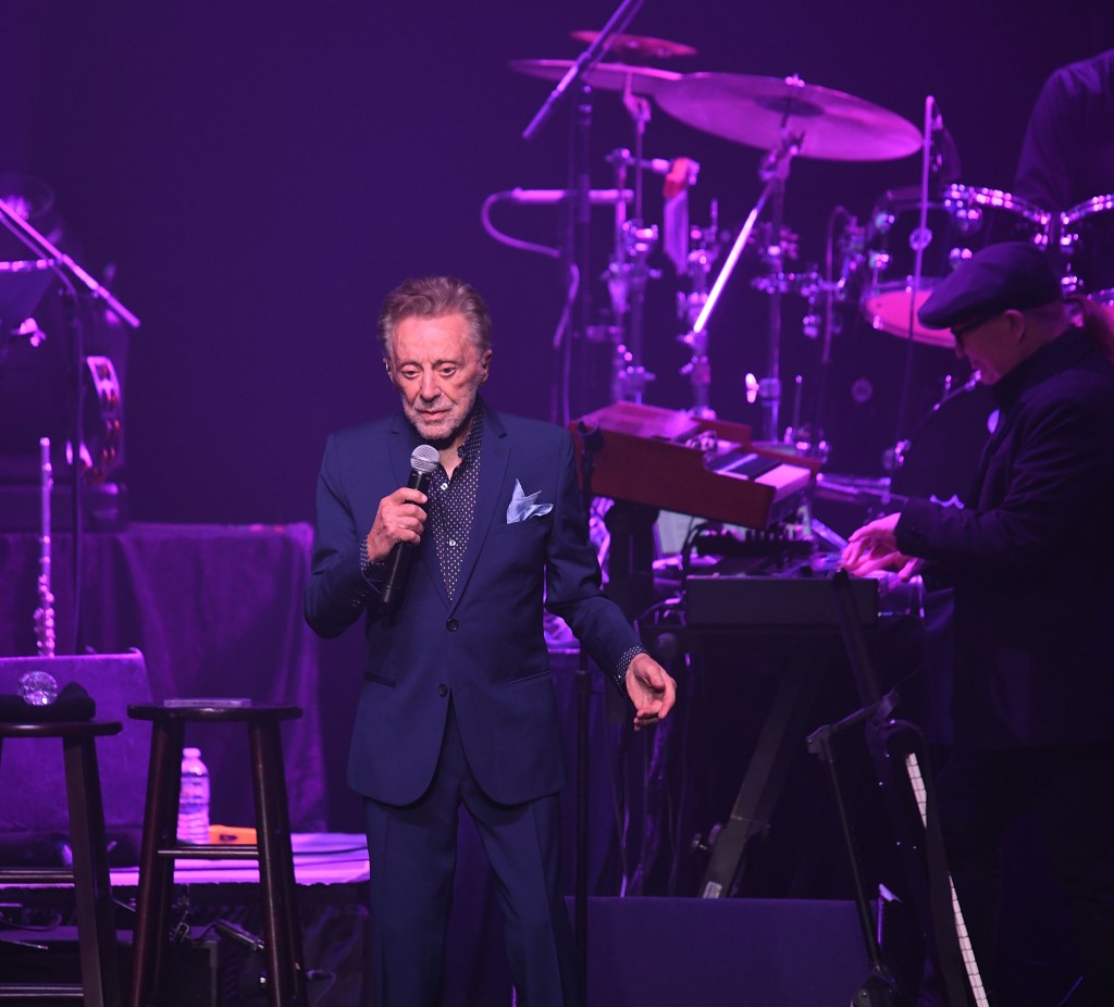 Frankie Valli performing on stage with The Four Seasons.