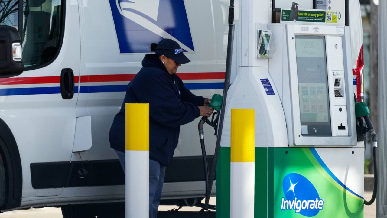 A woman holds a fuel pump nozzle to fill up a USPS vehicle's tank at a gas station, in Chicago, Tuesday, April 7, 2026. (AP Photo/Nam Y. Huh)