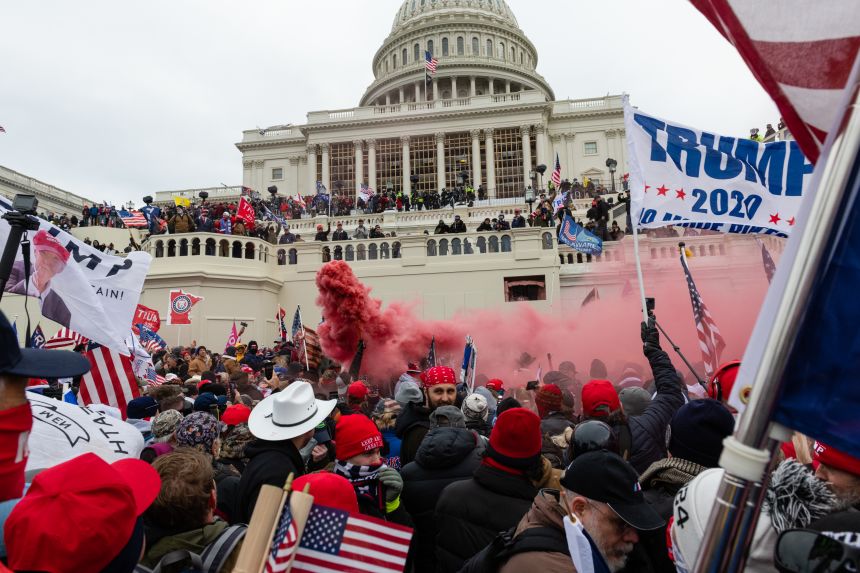 A demonstrator unleashes a smoke grenade in front of the U.S. Capitol building during a protest in Washington, DC, on January 6, 2021. The US Capitol was placed under lockdown as hundreds of protesters swarmed past barricades surrounding the building where lawmakers were debating Joe Biden's victory in the Electoral College.