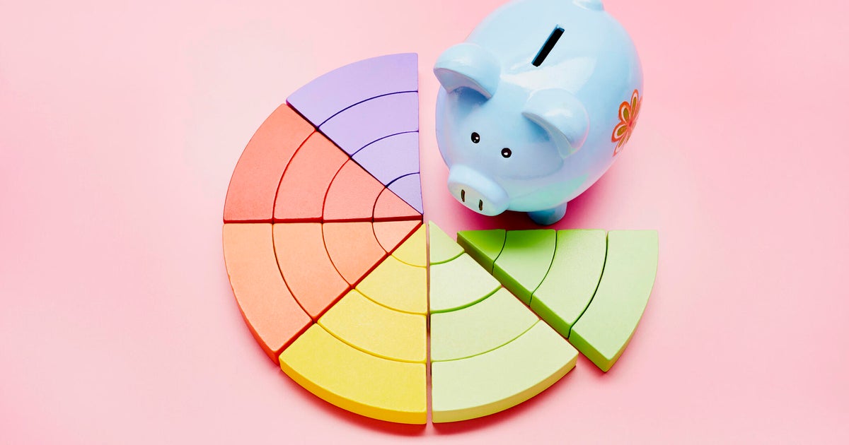 High angle view of a piggy bank and colorful pie chart on pink background