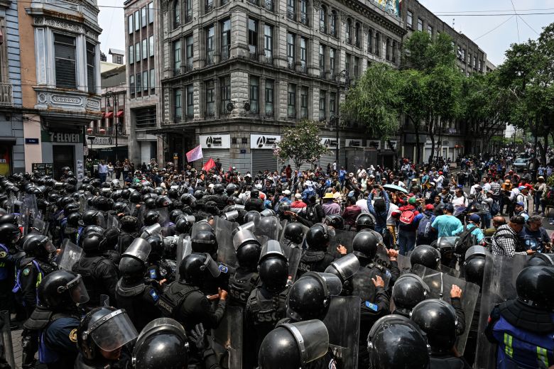 Teachers from the National Coordinator of Education Workers are held back by riot police during a protest march attempting to reach the Zocalo, where a Fan Fest is being set up for the FIFA World Cup, in Mexico City, on May 25, 2026. Teachers are calling for a general strike and protests around stadiums hosting World Cup matches.