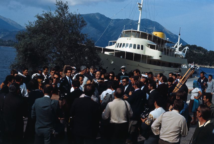 A crowd of reporters surrounds Jackie Kennedy after she arrived on the Greek island of Skorpios by the yacht Christina, after recently announcing she would marry Aristotle Onassis.