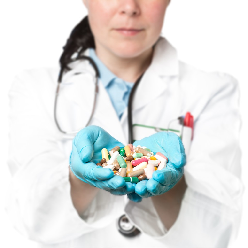 A doctor in blue gloves and a white coat holds a handful of colorful pills.